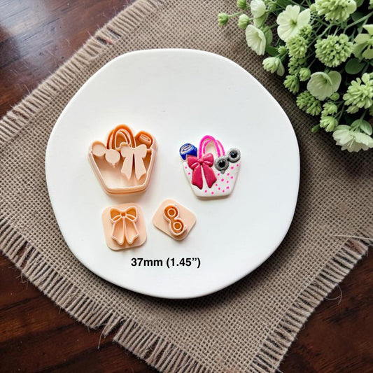 Summer handbag cutter, finished sample, bow stamp, and sunglasses stamp displayed together on a white ceramic dish showing the 37mm (1.45") size.