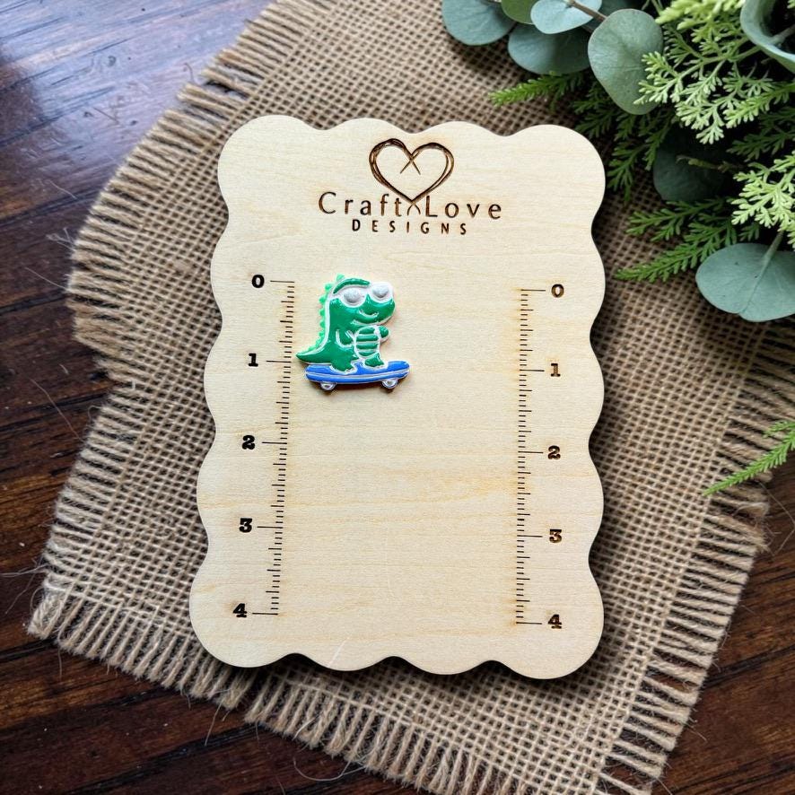Finished green gator wearing sunglasses and riding a blue skateboard, displayed on a Craft Love Designs measurement board.
