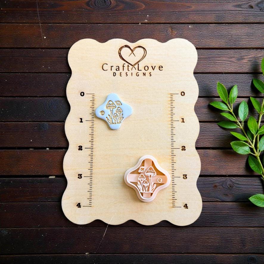 Finished light blue clay piece with a detailed gold mushroom cluster beside the matching polymer clay cutter on a measurement board.