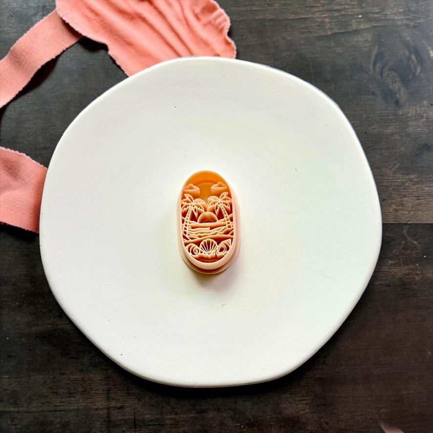 Tropical Beach Sunset polymer clay cutter displayed on a white ceramic plate.