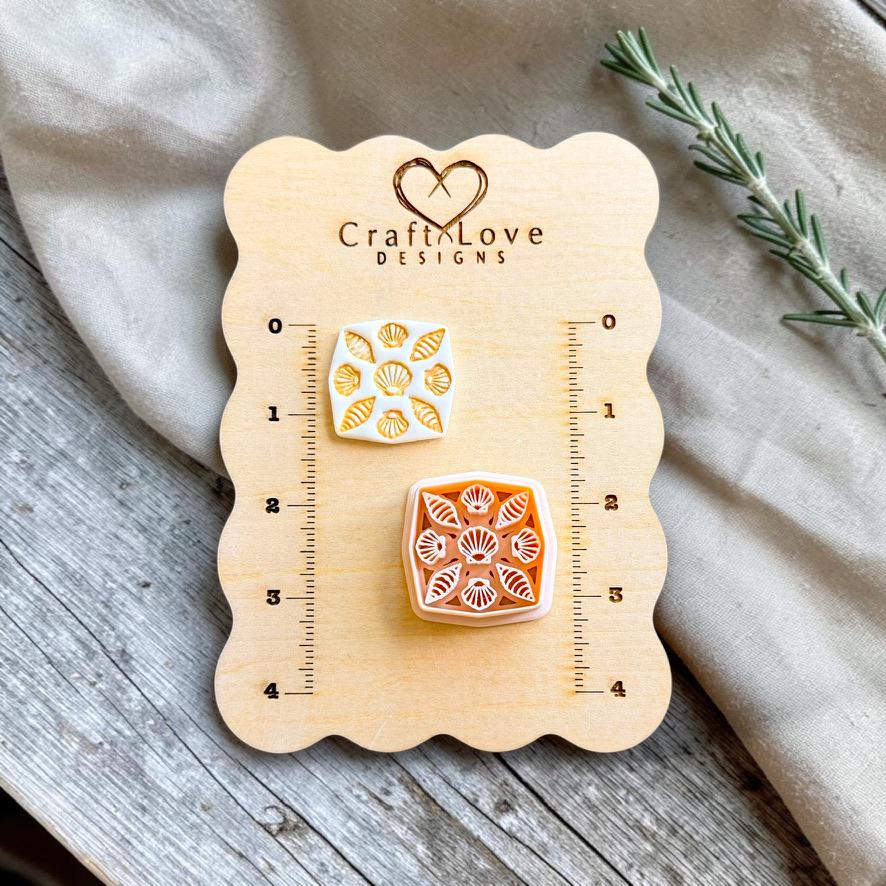 Finished polymer clay earring featuring a square seashell tile pattern displayed beside the matching cutter on a Craft Love Designs sizing board.