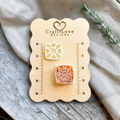 Finished polymer clay earring featuring a square seashell tile pattern displayed beside the matching cutter on a Craft Love Designs sizing board.
