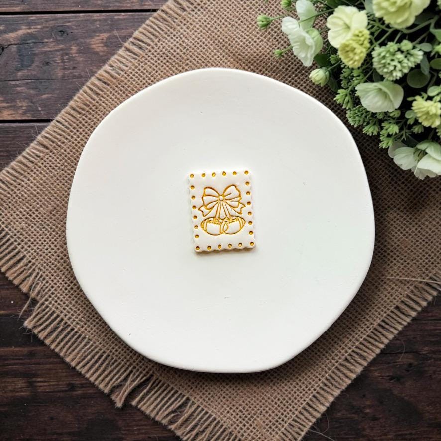 Finished football cherry embossed clay sample with bow on a white ceramic dish.