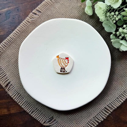 Chicken polymer clay embossed sample displayed on a white ceramic dish.