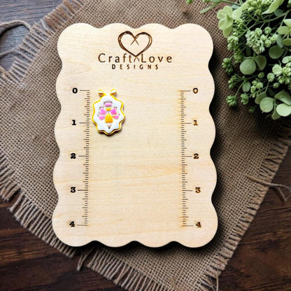 Finished pencil with bow framed polymer clay earring displayed on the Craft Love Designs measurement board.