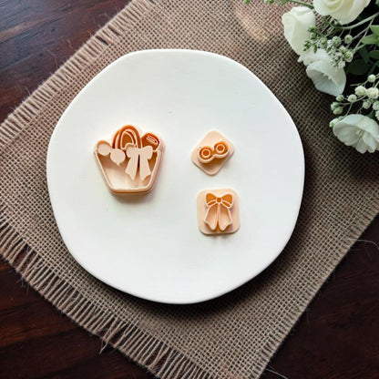 Summer handbag cutter with separate bow and sunglasses stamps displayed on a white ceramic dish.
