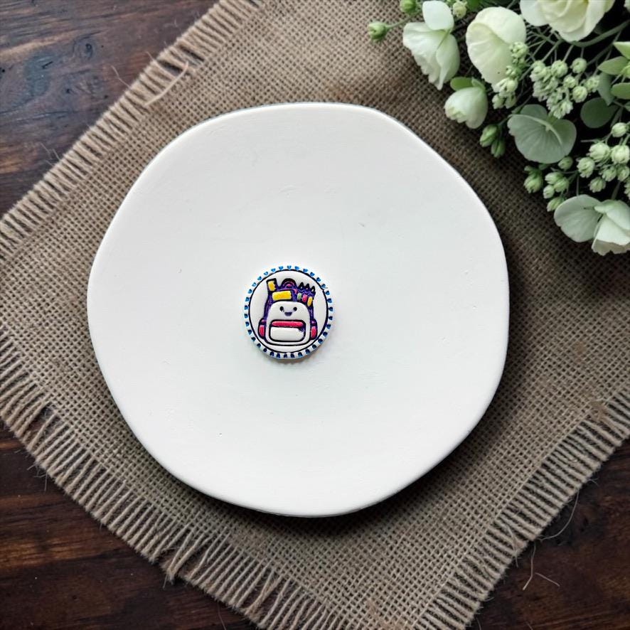 Finished colorful bookbag with classroom supplies inside an oval border, displayed on a white plate.
