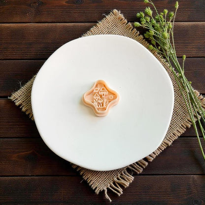 Mushroom polymer clay cutter featuring a detailed cluster of toadstools and woodland elements displayed on a white plate with rustic greenery.