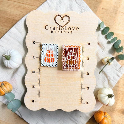 Finished white polymer clay piece with three stacked orange pumpkins beside the matching rectangular pumpkin clay cutter on a measurement board.
