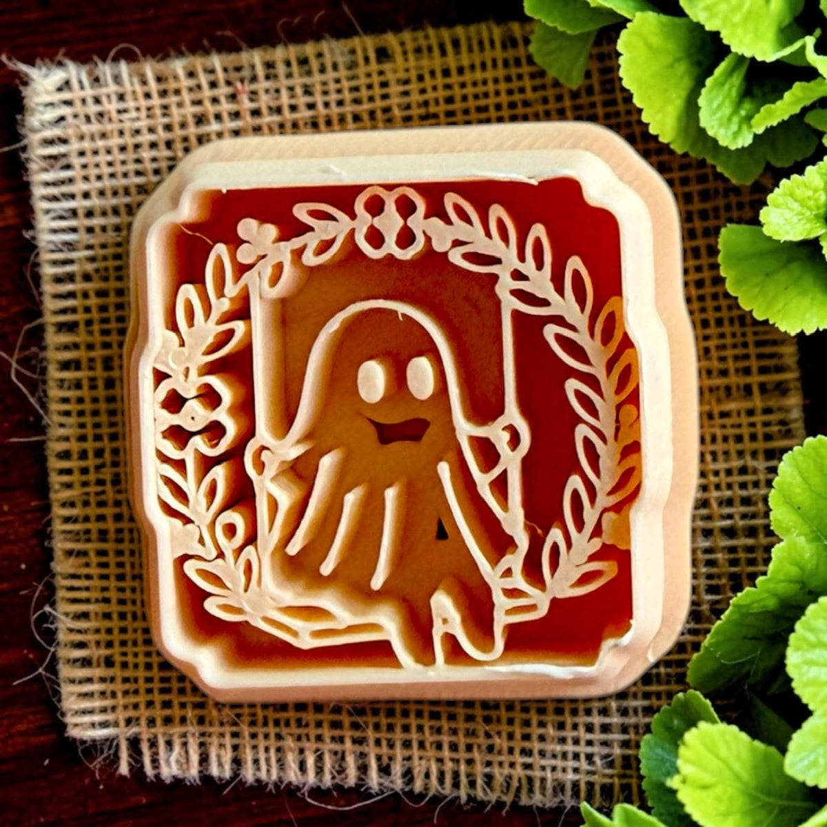 Close-up of floral ghost polymer clay cutter featuring a smiling ghost framed by a botanical wreath.