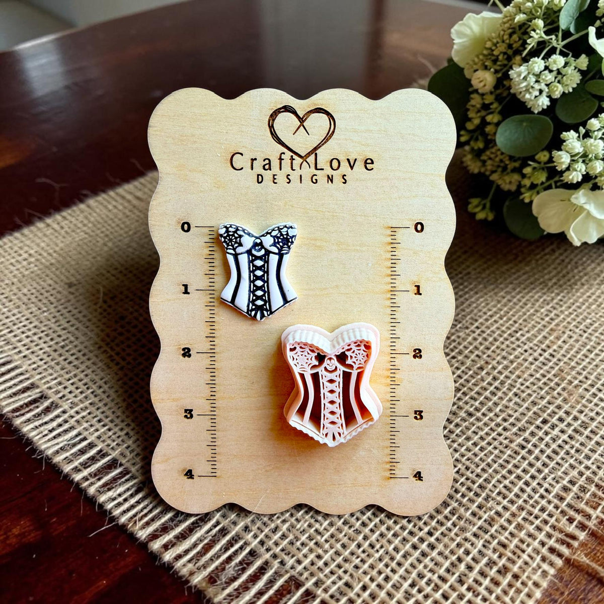 CraftLove Designs display board showing finished corset earring beside the matching 40mm spooky corset polymer clay cutter.