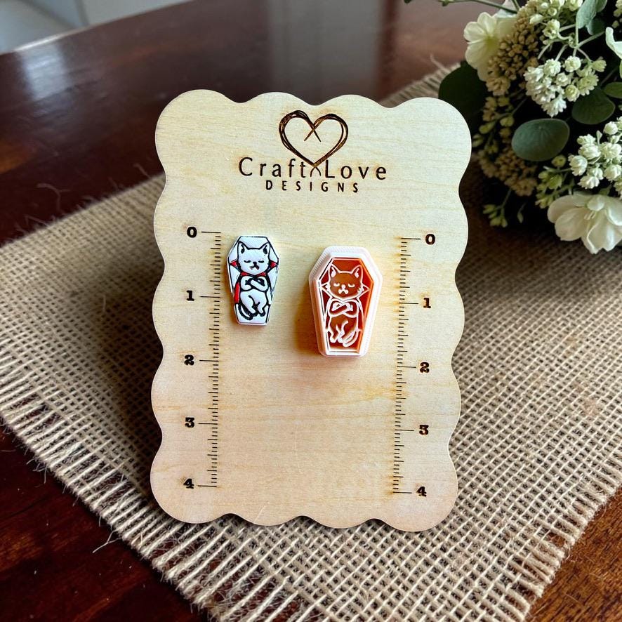 Vampire cat polymer clay cutter displayed beside a finished coffin-shaped clay piece on a Craft Love Designs sizing board.
