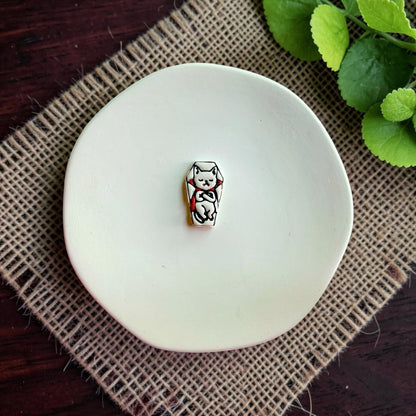 Finished coffin-shaped vampire cat clay piece displayed on a white dish.