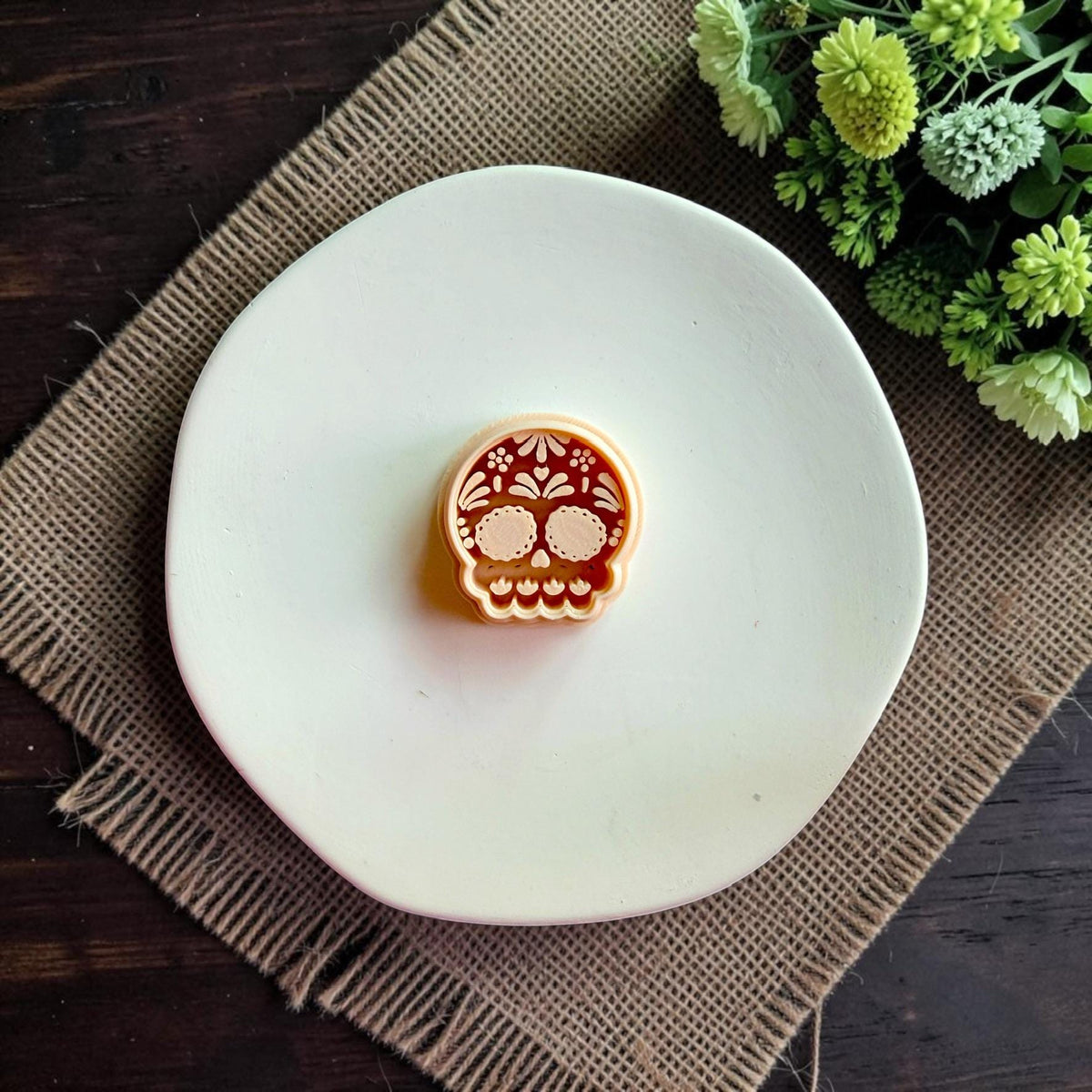 Sugar Skull polymer clay cutter shown on white clay displaying detailed floral calavera design.