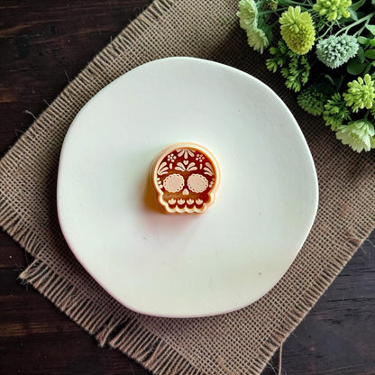 Sugar Skull polymer clay cutter shown on white clay displaying detailed floral calavera design.