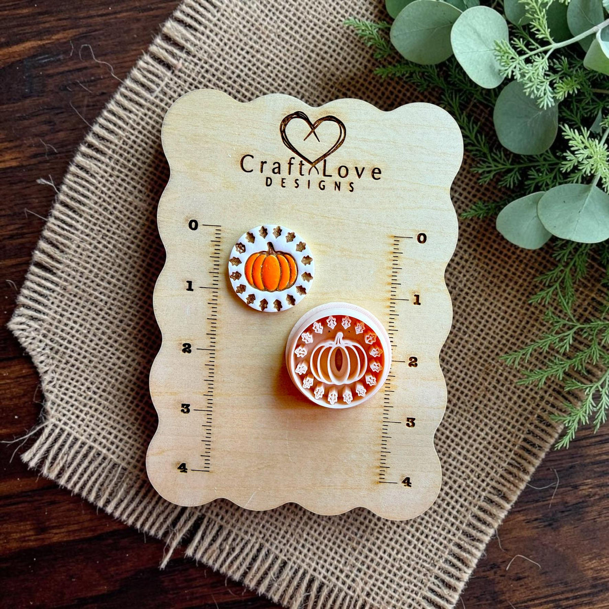 Pumpkin polymer clay cutter displayed beside a finished clay pumpkin earring on a Craft Love Designs size board.