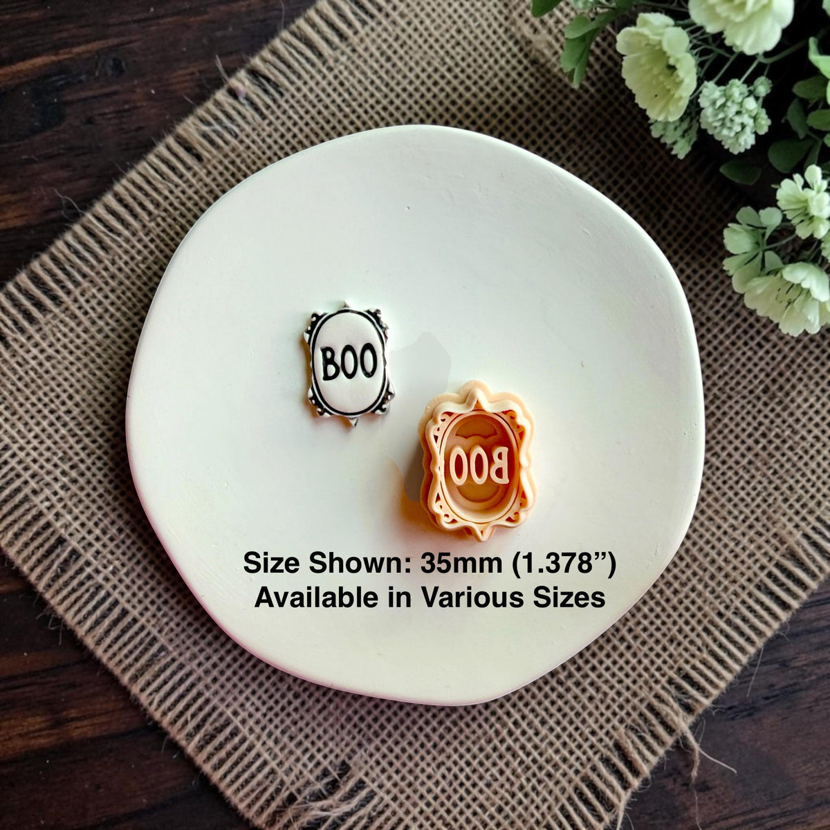 Finished Boo clay design beside the matching polymer clay cutter on a white dish.