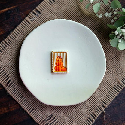 Finished stacked pumpkin clay design with a bow displayed alone on a white dish.