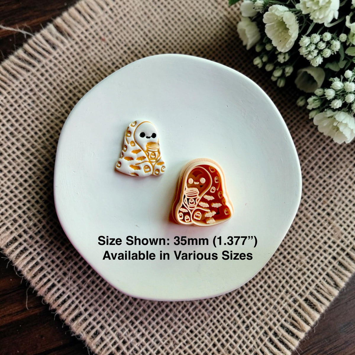 Finished cozy ghost holding a coffee cup beside the matching polymer clay cutter with size information shown.