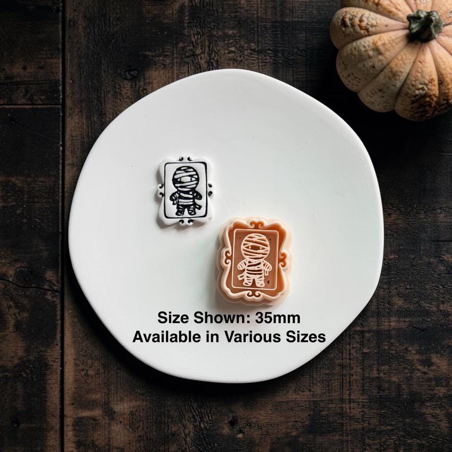 Finished black and white mummy clay piece beside the peach framed mummy design on a white clay slab; text states size shown is 35mm and available in various sizes.