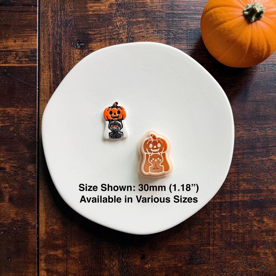 Finished orange, white, and black Pumpkin Ghost with Kitty piece displayed beside the matching peach-colored polymer clay cutter on a white plate.