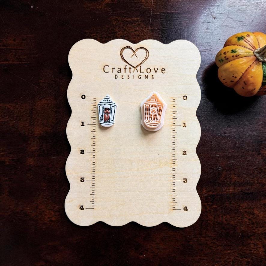 Finished miniature Halloween lantern clay piece displayed beside the matching peach polymer clay cutter on a wooden measuring board, featuring a small bat inside the lantern.