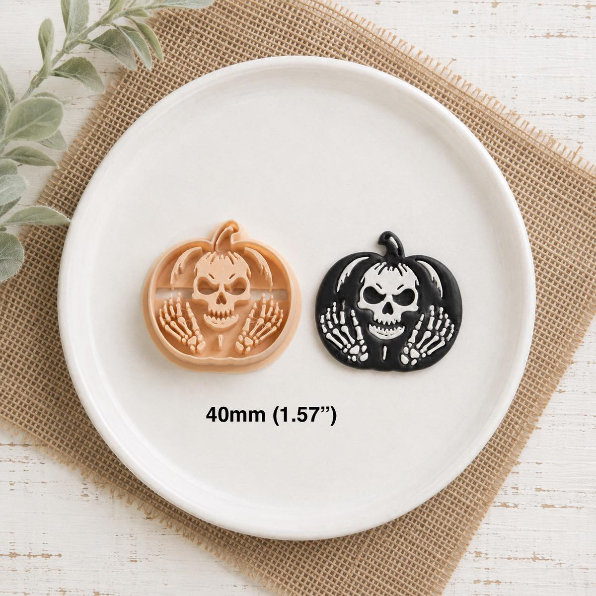 Peach skeleton pumpkin clay design beside the finished black and white example on a white plate, showing the skull and skeletal hand details with 40mm (1.57 inches) size text.