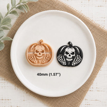 Peach skeleton pumpkin clay design beside the finished black and white example on a white plate, showing the skull and skeletal hand details with 40mm (1.57 inches) size text.