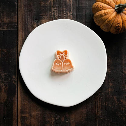 Peach ghost cherries design centered on a white plate, featuring two ghost shapes connected by stems beneath a bow.