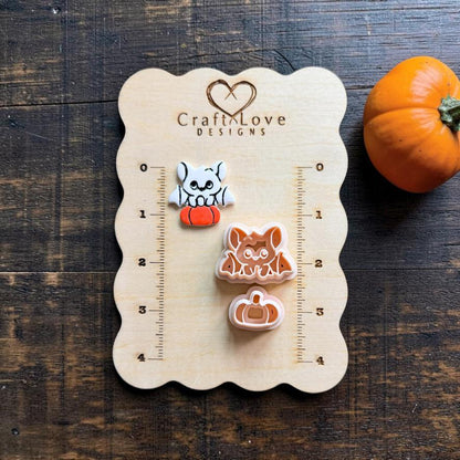 Finished white and orange bat on pumpkin clay piece beside the matching peach bat and separate pumpkin designs on a Craft Love Designs wooden measuring board.