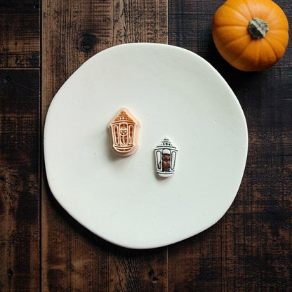 Matching bat lantern polymer clay cutter and finished decorated clay example displayed together on a white plate with an orange pumpkin in the background.