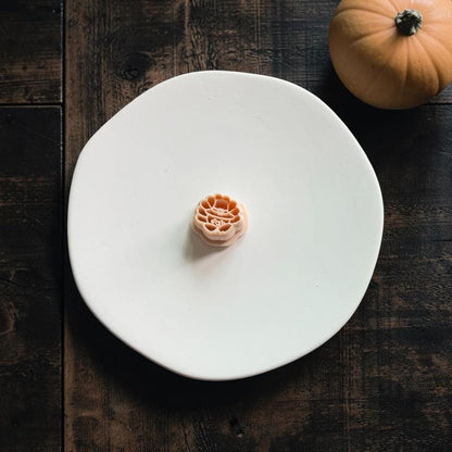 Peach cute turkey polymer clay cutter centered on a white plate with a small pumpkin in the upper corner.
