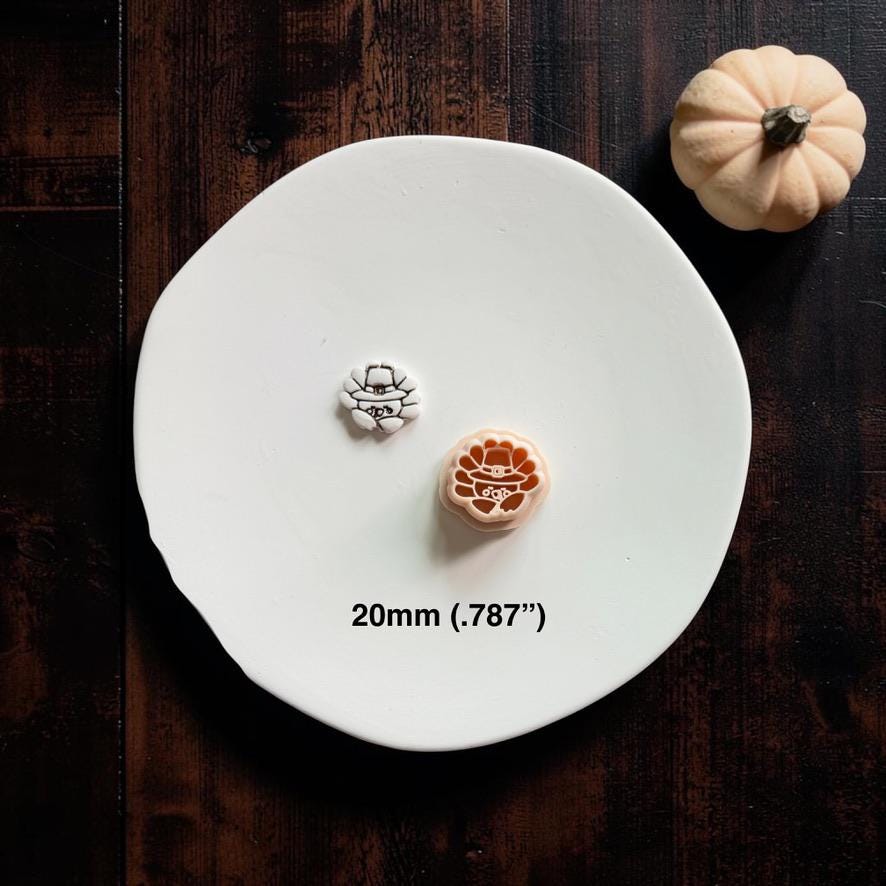 Finished cute turkey clay piece displayed beside the matching peach turkey polymer clay cutter on a white plate with a small pumpkin.