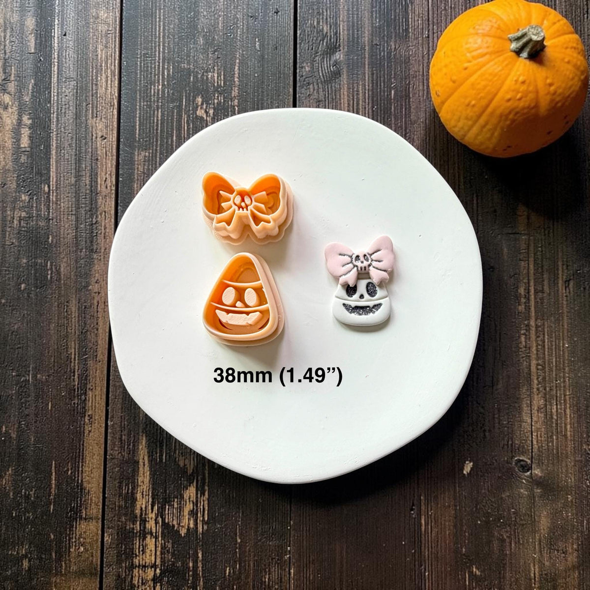 Peach candy corn and skull bow pieces displayed beside a finished white candy corn face topped with a pale pink bow and small skull detail on a white plate.