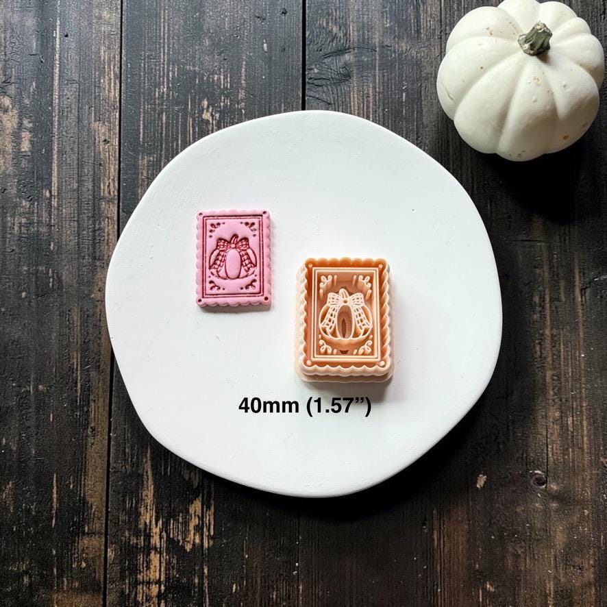 Finished pink pumpkin-and-bow frame beside the peach-colored design on a white round surface with a white pumpkin nearby; text shows the size as 40mm (1.57").