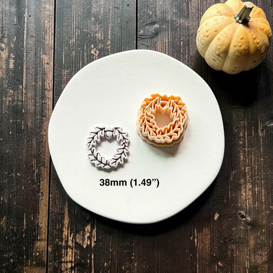 Finished white oak leaf and acorn wreath beside the orange polymer clay cutter on a white round surface, with text showing the 38mm (1.49") size.