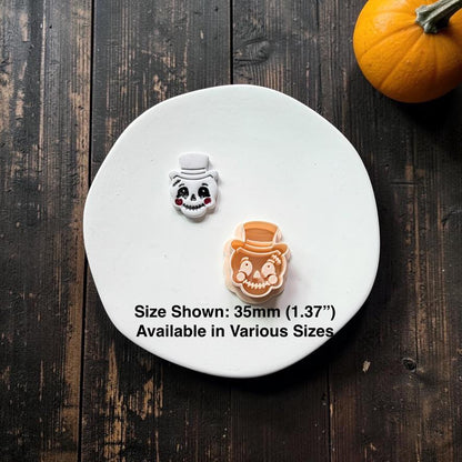 Finished vintage top hat pumpkin face beside the peach-colored polymer clay cutter, with text stating size shown is 35mm (1.37") and available in various sizes.