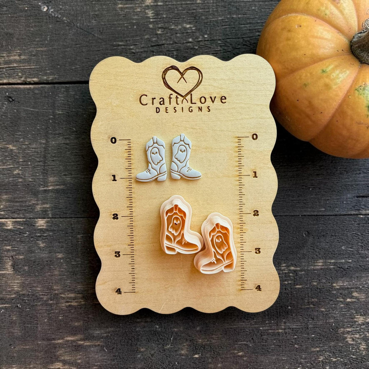 Mirrored ghost cowboy boot clay cutter pair displayed with finished light-colored boot examples on a wooden Craft Love Designs measuring board.