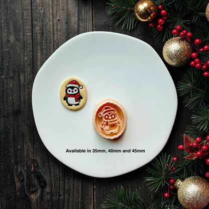 Finished black, white, and red Christmas penguin piece beside the matching larger design on a white plate, with text showing available sizes of 35mm, 40mm, and 45mm.