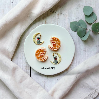Mirrored cat and crescent moon designs shown with their finished clay examples on a white plate, with each cat facing the opposite direction and text showing the 35mm (1.37 inch) size.