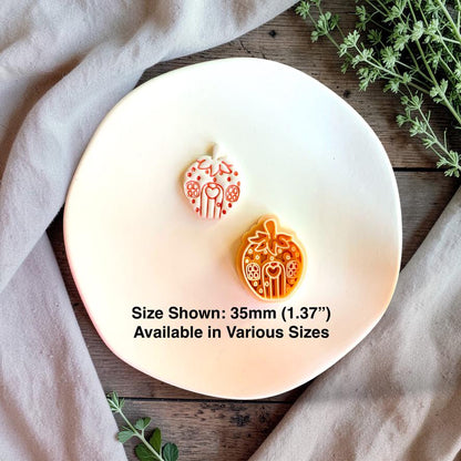 Finished white strawberry house clay piece displayed beside the orange design on a white plate, with text stating size shown is 35mm (1.37 inches) and various sizes are available.