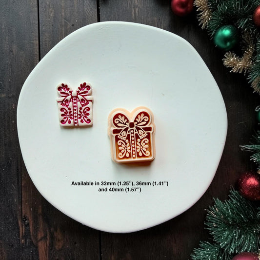 Small white and red Christmas present beside a larger red and cream version on a white surface. Both feature decorative bows, ribbons, dots, and floral folk art details. Available sizes shown are 32mm (1.25"), 36mm (1.41"), and 40mm (1.57").