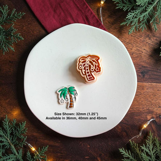 Christmas palm tree polymer clay cutter beside the finished colorful palm tree clay piece on a white plate, with text showing the 32mm size pictured and availability in 36mm, 40mm, and 45mm.