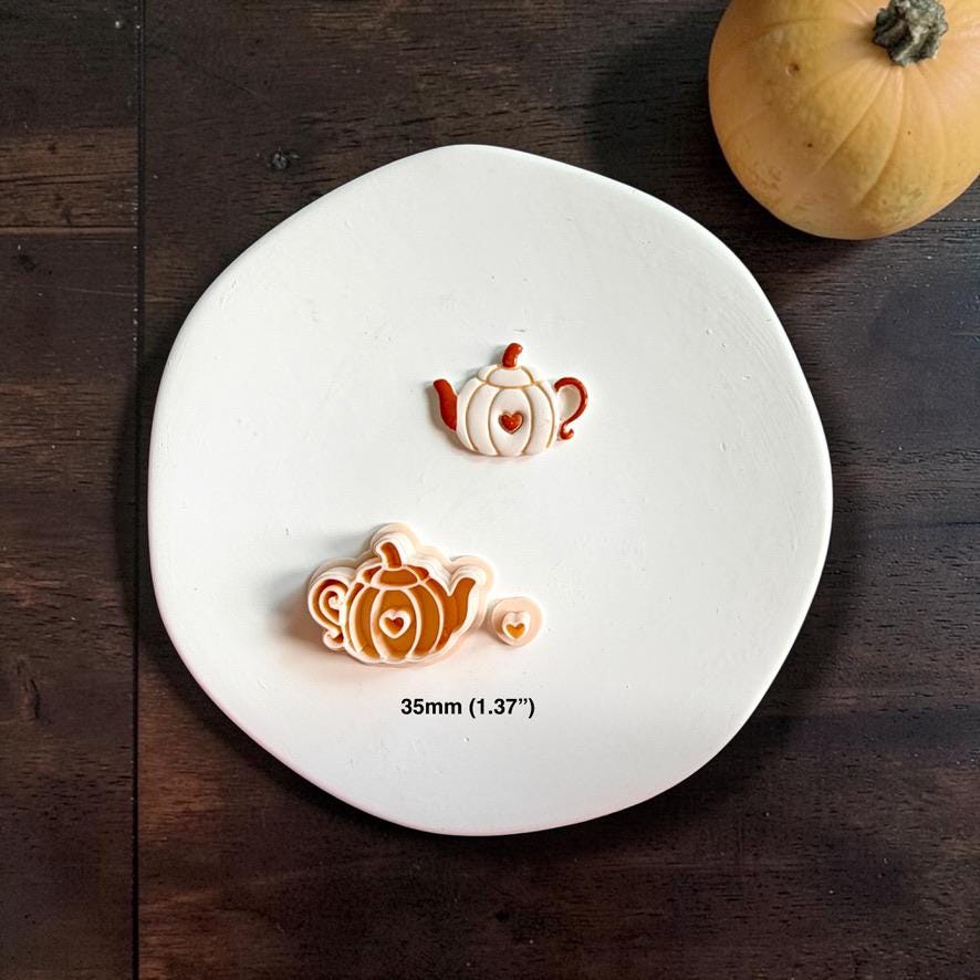 Finished pumpkin teapot clay piece, matching cutter, and small heart-shaped piece displayed on a white plate, with text showing the size as 35mm or 1.37 inches.