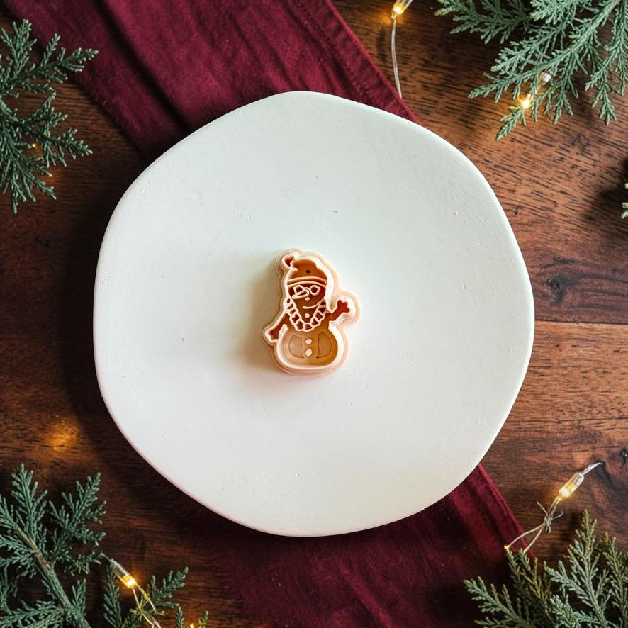 Tropical snowman polymer clay cutter centered on a white plate, showing the snowman shape with Santa hat, sunglasses, lei, arms, and body details.