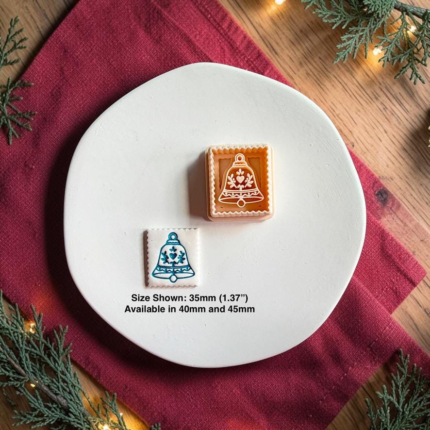 Decorative Christmas bell polymer clay cutter beside the finished white bell clay piece on a white plate, with text showing the 35mm size pictured and availability in 40mm and 45mm.