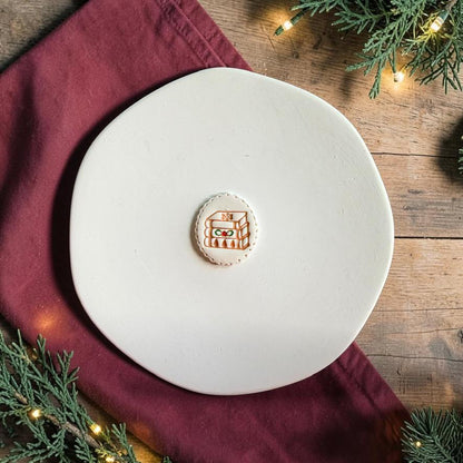 Finished winter holiday stack of books clay piece centered on a white plate with a soft holiday-themed background.