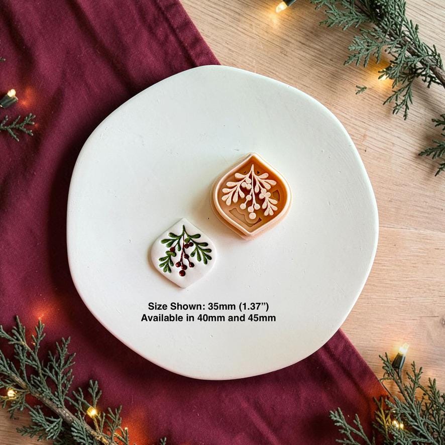 Mistletoe polymer clay cutter beside the finished white botanical clay piece on a white plate, with text showing the 35mm size pictured and noting availability in 40mm and 45mm.