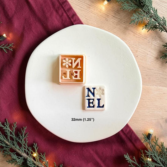 NOEL polymer clay cutter beside the finished white letter tile on a white plate, with text showing the 32mm or 1.25 inch size.