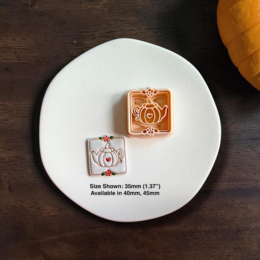 Pumpkin teapot polymer clay cutter beside the finished white clay piece on a white plate, with text showing the 35mm size pictured and availability in 40mm and 45mm.